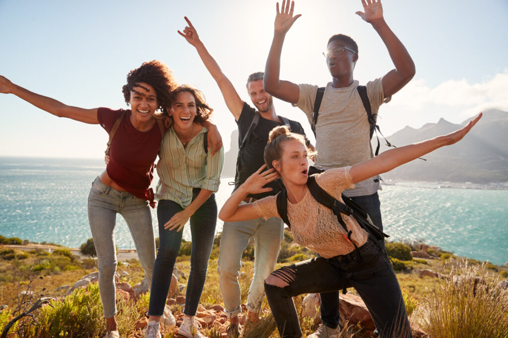 Des amis du millénaire en randonnée célèbrent leur arrivée au sommet et s'amusent à poser pour des photos | Millennial friends on a hiking trip celebrate reaching the summit and have fun posing for photos