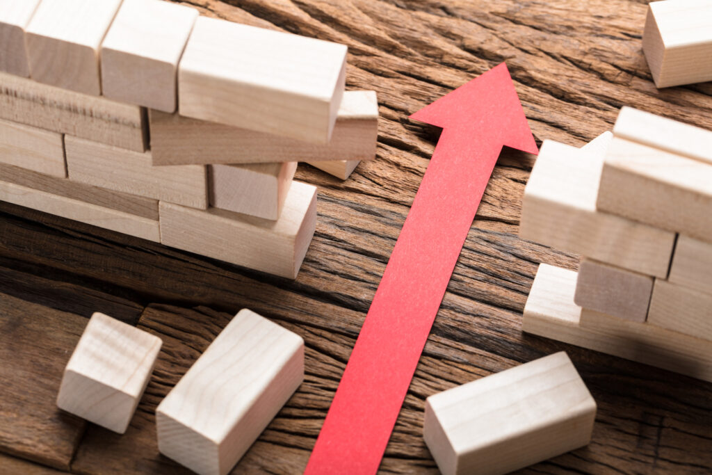 High angle view of red paper arrow amidst blocks on wooden table | Vue grand angle de la flèche de papier rouge au milieu des blocs sur la table en bois