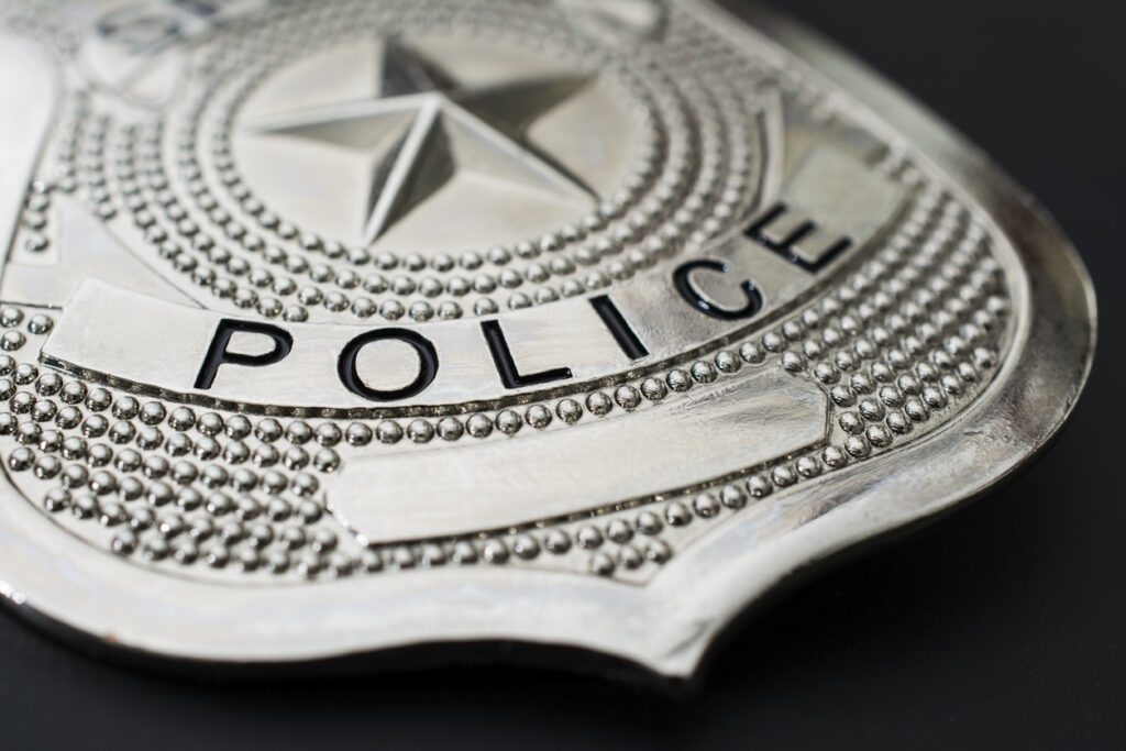 Silver police badge macro photo on black background.