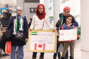 Toronto, Canada - December 11, 2015: Sponsors, family, and Canadians simply wishing to welcome their new neighbours await the first plane's arrival of Syrian refugees at Toronto's Pearson International Airport. | Toronto, Canada - 11 décembre 2015 : Les commanditaires, la famille et les Canadiens qui souhaitent simplement accueillir leurs nouveaux voisins attendent l'arrivée du premier avion de réfugiés syriens à l'aéroport international Pearson de Toronto.