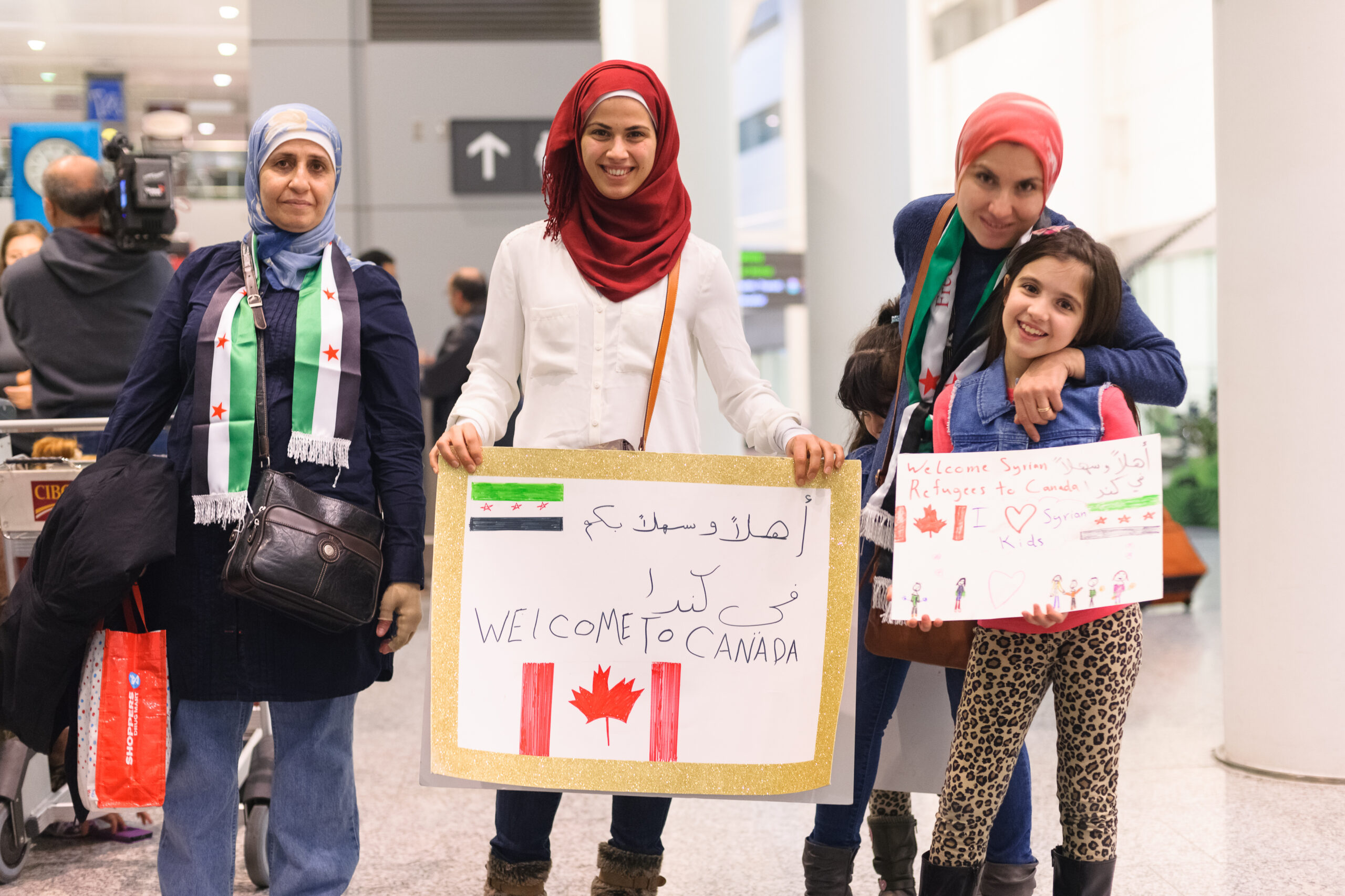 Toronto, Canada - December 11, 2015: Sponsors, family, and Canadians simply wishing to welcome their new neighbours await the first plane's arrival of Syrian refugees at Toronto's Pearson International Airport. | Toronto, Canada - 11 décembre 2015 : Les commanditaires, la famille et les Canadiens qui souhaitent simplement accueillir leurs nouveaux voisins attendent l'arrivée du premier avion de réfugiés syriens à l'aéroport international Pearson de Toronto.