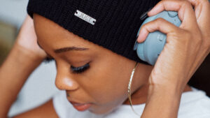 Young woman weaing a beanie hat puts on headphones