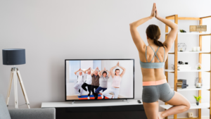 Woman follows a yoga program on the TV