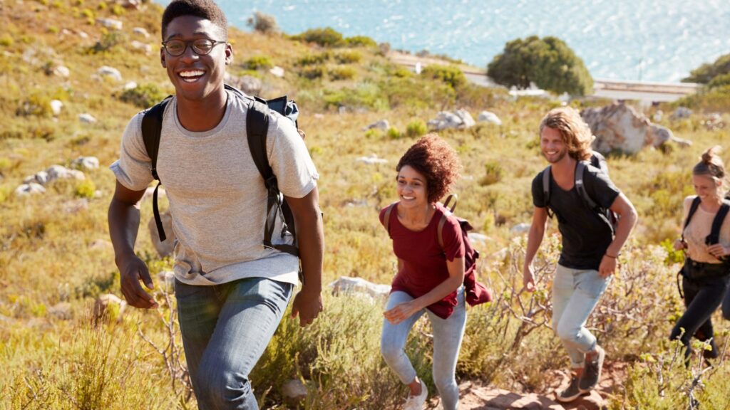 A group of young-looking hikers taking a walk on mountainous trail on a sunny day