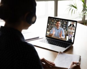 Pc screen view over woman shoulder during group videocall elearning