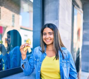 A young woman holding a yellow ribbon in front of a window.