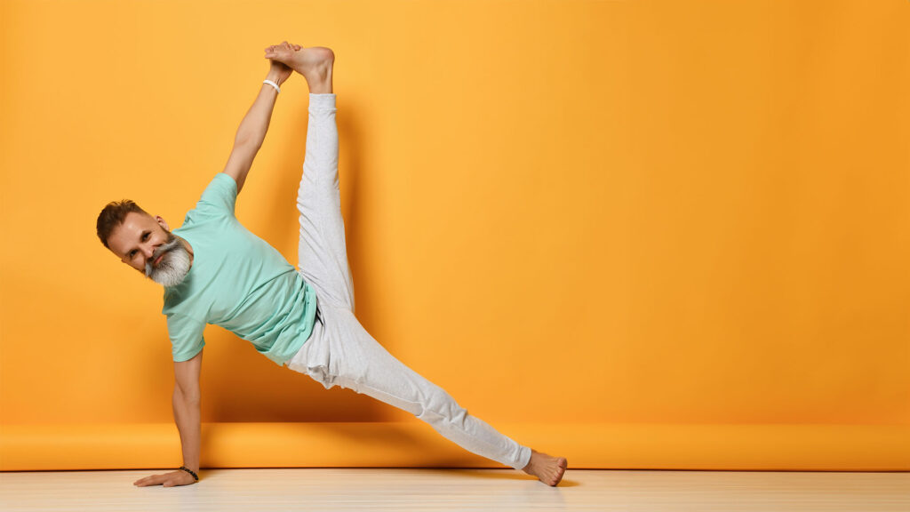Man doing yoga stretches again a bright yellow wall