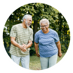 Two elderly people walking through the forest.