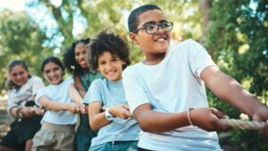A group of children collaborating, exerting effort as they pull a rope together in unison.