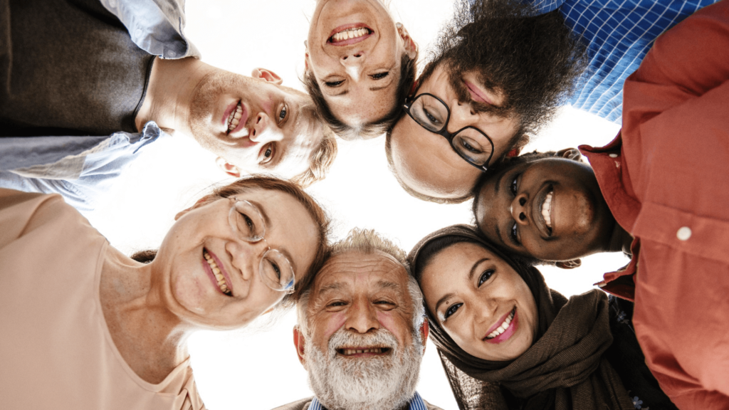 A diverse group of people stand together in a circle
