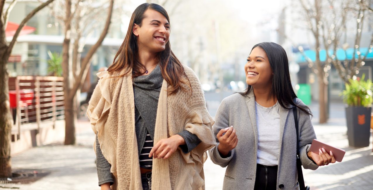 Cropped shot of two affectionate young friends having a discussion while walking in the city