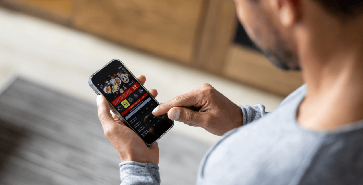 A man staring at a gambling app on his phone