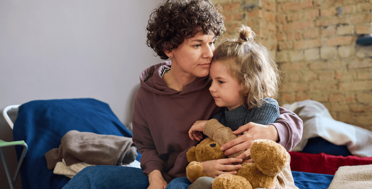 Main Image A woman comforting her daughter at a shelter